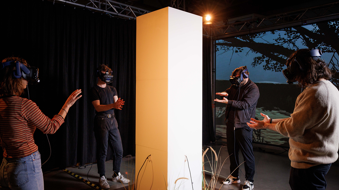 Photo de quatre usagers portant des casques de réalité virtuelle et interagissant avec l'expérience Chomsky. 